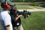 Ofc. Blount stands by as Julie Rogers takes aim with an M-16.